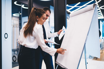 Formally dressed male and female partners with paper documents discussing executive information...