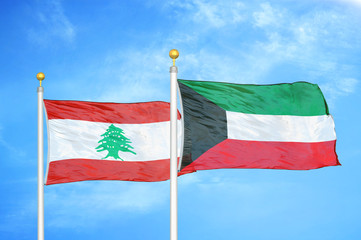 Lebanon and Kuwait two flags on flagpoles and blue cloudy sky