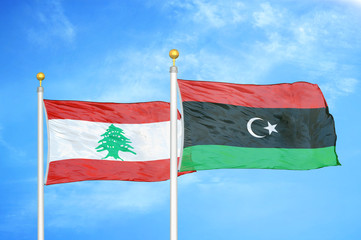 Lebanon and Libya two flags on flagpoles and blue cloudy sky