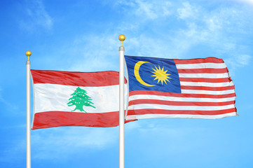 Lebanon and Malaysia two flags on flagpoles and blue cloudy sky