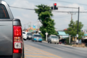 Luxury of pickup gray car stop on the junction by traffic light control in across. Traveling in the provinces during the bright period. Open light brake. Blurred images of traffic jams opposite.