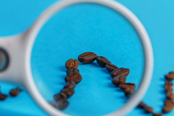 Coffee beans on a blue cyan background through a magnifier