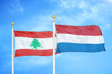 Lebanon and Netherlands two flags on flagpoles and blue cloudy sky