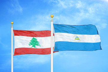 Lebanon and Nicaragua two flags on flagpoles and blue cloudy sky