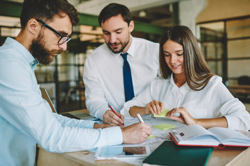 Group of male and female colleagues discussing ideas for startup project creating new architect sketches together, Caucasian persons 30s cooperating on graphs brainstorming in company office