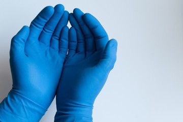 Doctors male hands in nitrile blue medical gloves holding his palms up like holding something. Closeup on isolated white background.
