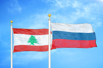 Lebanon and Russia two flags on flagpoles and blue cloudy sky