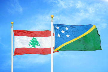 Lebanon and Solomon Islands two flags on flagpoles and blue cloudy sky