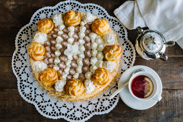 Cream cake decorated with cream puffs filled with cream and chocolate.