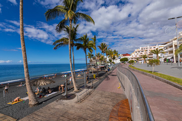 Palms  at beach with black lava sand at Puerto Naos in La Palma Island, Canary Island, Spain.