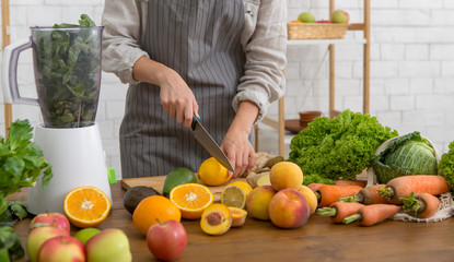 Woman cutting fruits on kitchen table. Healthy detox diet