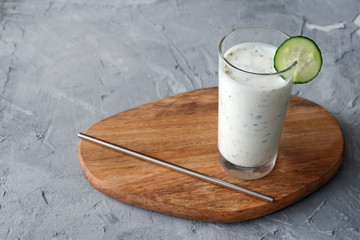 Turkish drink Ayran or Kefir (fresh homemade yogurt) with herbs and cucumbers in glass, with reusable stainless steel straw