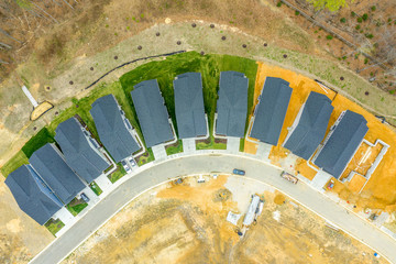 Aerial top down view of a new American residential neighborhood under construction forming a crescent shape, some single family houses are already occupied some still being built