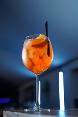 Low angle shot of bitter Aperol spritz on blue neon background