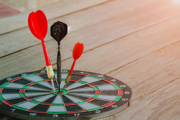 Fototapeta premium red and Black Dart arrow hitting on center dart board, Success hitting target aim goal achievement concept background – three dart in bull’s eye close up,