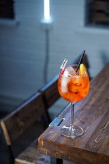 Aperol spritz with a slice of orange on wooden bar counter, atmospheric shot