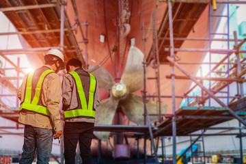 Engineer, surveyor at stern and ship propeller, rudder red after maintenance already by in floating...