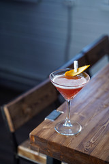 Cosmopolitan cocktail on wooden table in a cold neon light of a loft bar