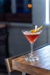 Cosmopolitan cocktail on wooden table in a cold neon light of a loft bar