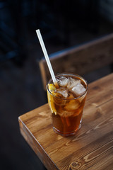 Modern classics mixology: cuba libre with rum and cola on wooden bar counter, atmospheric shot