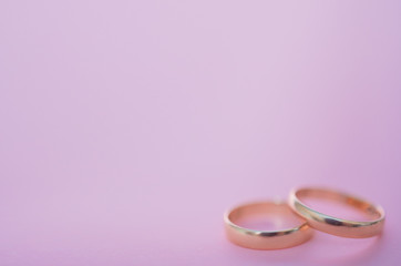 Two gold wedding rings of the bride and groom, husband and wife lie in the form of an infinity sign on a pink background, top view: wedding concept, Valentine's day