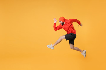 Fototapeta na wymiar Side view of screaming young fitness sporty guy 20s sportsman in hat hoodie shorts in home gym isolated on yellow background in studio. Workout sport motivation lifestyle concept. Jump like running.