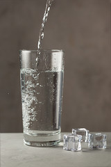 Glass with water and ice on gray surface