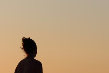 silhouette d'un visage féminin avec les cheveux au vent en contre jour au coucher de soleil avec...