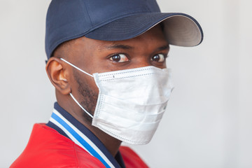 Close up photo of handsome african man in a cap and casual clothes wearing medical mask shocked with coronavirus 2019 danger