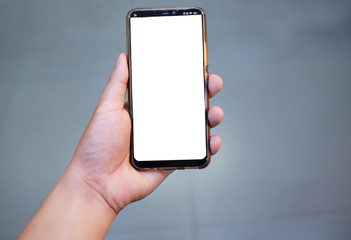 Hand holding a smartphone on gray background.