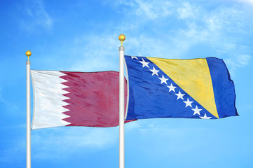 Qatar and Bosnia and Herzegovina  two flags on flagpoles and blue cloudy sky