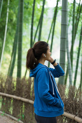 A young Asian woman walks and rests in a bamboo forest