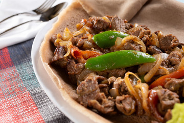 A closeup view of a plate of beef tibs, in a restaurant or kitchen setting.