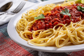 A closeup view of a plate of spaghetti and meat sauce, in a restaurant or kitchen setting.