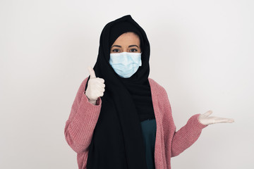 Young happy cheerful woman showing thumb up and pointing with the other hand while standing outdoors. Good Job. Wearing casual clothes.