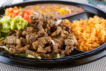 A closeup view of a plate of carne asada, in a restaurant or kitchen setting.