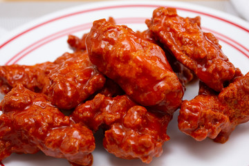 A closeup view of a plate of buffalo wings, in a restaurant or kitchen setting.