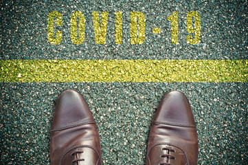 concept message on the road with feet - yellow line - COVID-19