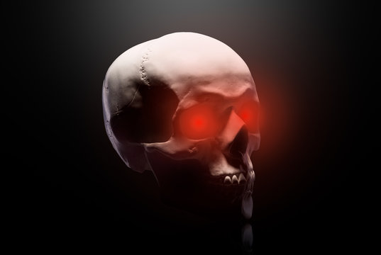 Model of the human skull with red eyes isolated on black background