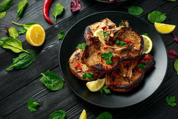 Homemade Grilled Pork loin chops in lemon sauce with herbs on rustic wooden table