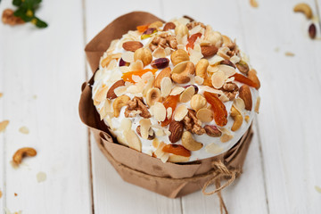 Easter cake decorated by nuts and dried fruits on white wooden background, Traditional Kulich, Paska  ready for celebration