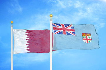 Qatar and Fiji two flags on flagpoles and blue cloudy sky