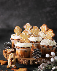 Christmas cupcakes with creamcheese frosting desorated with a gingerbread cookies. Close up view, vertical composition, selective focus.
