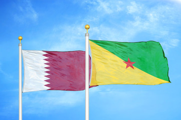 Qatar and French Guiana two flags on flagpoles and blue cloudy sky