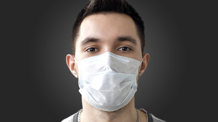 A person wears a protective mask to prevent the spread of airborne coronavirus infection 2019-nCov. Studio photo, banner, on a dark background.