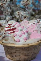 Colorful easter egg cookies in basket. Easter homemade gingerbread cookie in blooming trees. Easter Postcard Template. Cookies in shape of eggs. Outdoor shooting in garden.Close up view. 