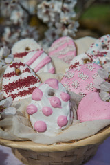 Colorful easter egg cookies in basket. Easter homemade gingerbread cookie in blooming trees. Easter Postcard Template. Cookies in shape of eggs. Outdoor shooting in garden.Close up view. 