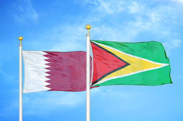 Qatar and Guyana two flags on flagpoles and blue cloudy sky