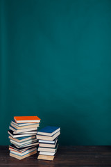 many stacks of educational books for learning preparation for college exams on a green background