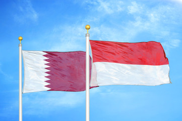 Qatar and Indonesia two flags on flagpoles and blue cloudy sky